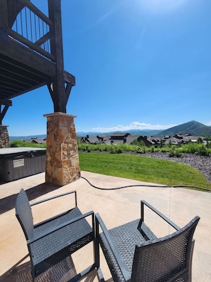 Une terrasse extérieure avec deux chaises en métal, un pilier en pierre et une vue sur une chaîne de montagnes.
