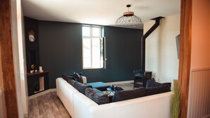 A modern living room with a white sofa, a coffee table, and a fireplace. - Cocon Bord de Lac, 11 Personnes, Piscine, Billard (PLIEUX)