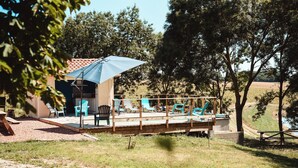 A deck with outdoor seating, a covered area, and a view of the surrounding landscape. - Cocon Bord de Lac, 11 Personnes, Piscine, Billard (PLIEUX)