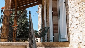 A stone building with a wooden porch and a staircase leading to the entrance. - Cocon Bord de Lac, 11 Personnes, Piscine, Billard (PLIEUX)