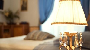 Une lampe avec un abat-jour plissé, posée sur une table de chevet dans une chambre d’hôtel.