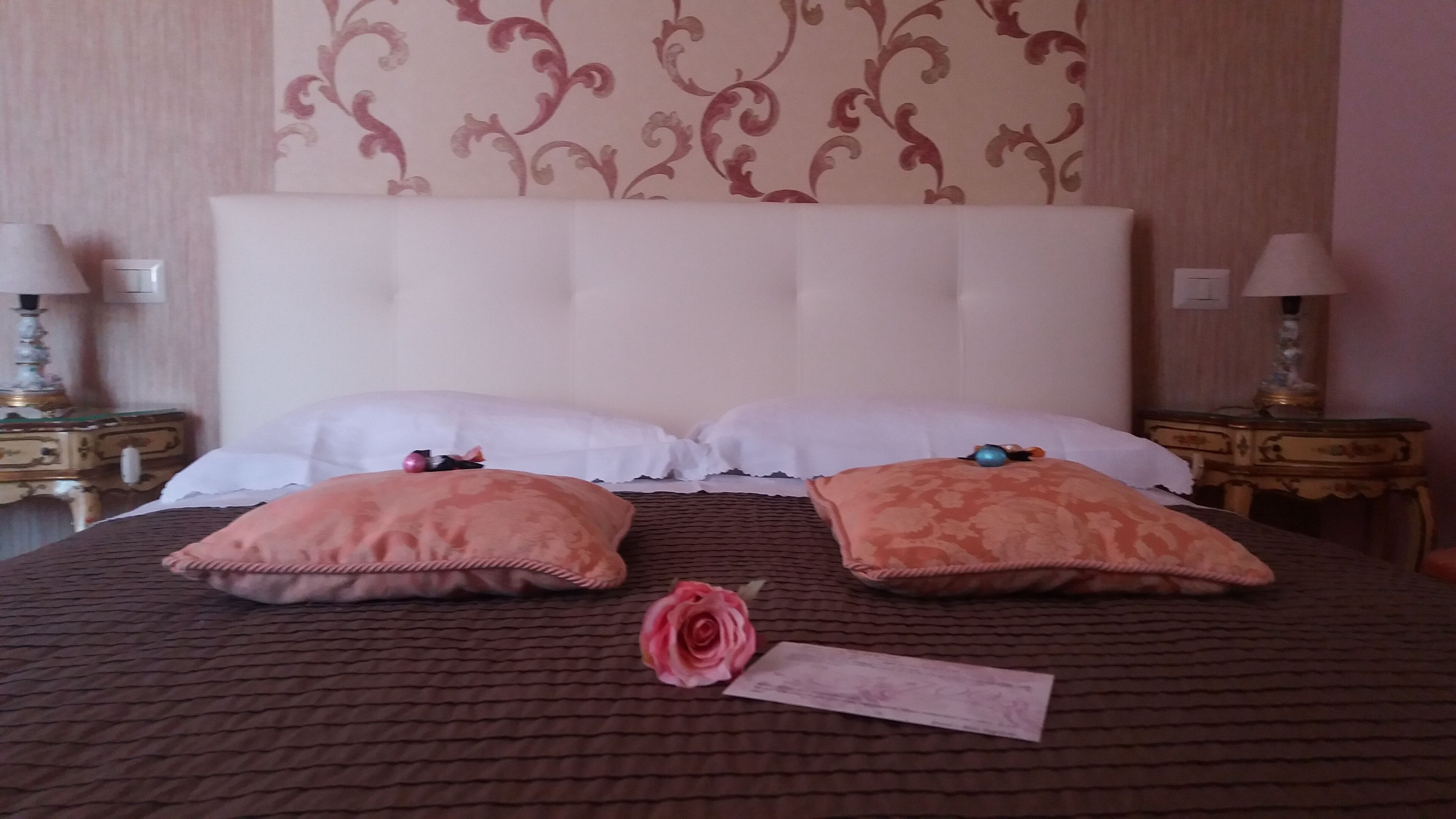 Un lit bien fait, avec deux oreillers, une rose et un chèque.
