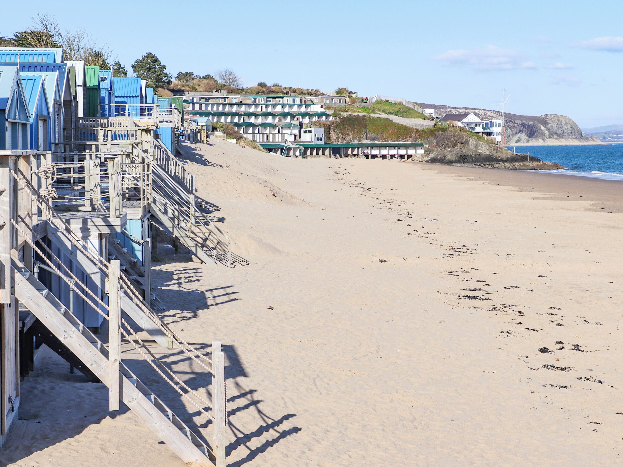 A beach with a wooden staircase leading to a building, a sandy beach, and a view of the sea.