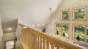 A wooden staircase with a railing, multiple windows with wooden frames, and recessed lighting.