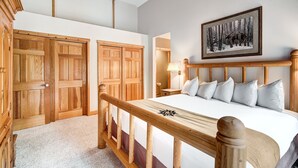 Ein Schlafzimmer mit einem großen Bett, einem hölzernen Kopfteil und einem gerahmten Bild an der Wand.