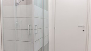 A glass-enclosed shower area with a door and a handle.