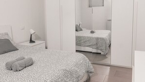 A bedroom with a bed, a nightstand, a lamp, and a wardrobe.
