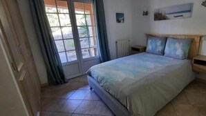 A bedroom with a bed, a window, a radiator, and a small shelf.