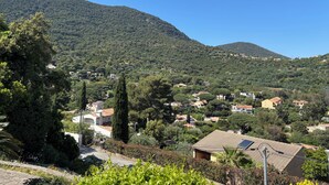 A hillside village with traditional architecture, a clear sky, and lush greenery.