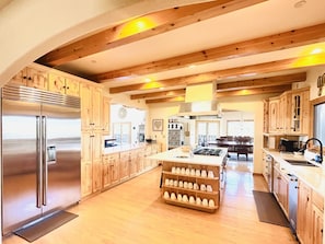 A spacious kitchen with wooden cabinets, a stainless steel refrigerator, and a central island with a sink. - H7 at Hope Mountain -- 6-Bedroom Retreat Home at Allenspark Colorado 6 Home by RedAwning (Allenspark)
