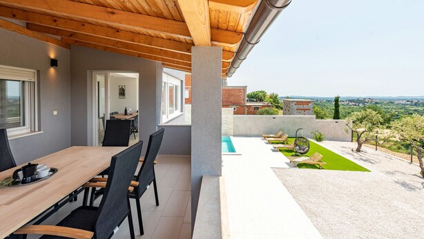 A covered patio with a dining area, a pool, and a view of the countryside. - Villa Pezer (Benkovac)
