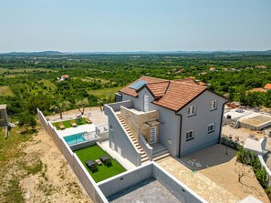 A modern two-story house with a swimming pool, a patio with outdoor furniture, and a view of the surrounding countryside. - Villa Pezer (Benkovac)