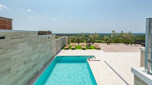 A swimming pool with a view of a landscaped area and distant hills. - Villa Pezer (Benkovac)