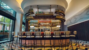 A bar area with multiple shelves of bottles, bar stools, and a patterned floor.