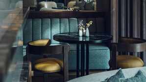 A modern restaurant interior with a cozy seating area, a round table with a vase of flowers, and pendant lighting.