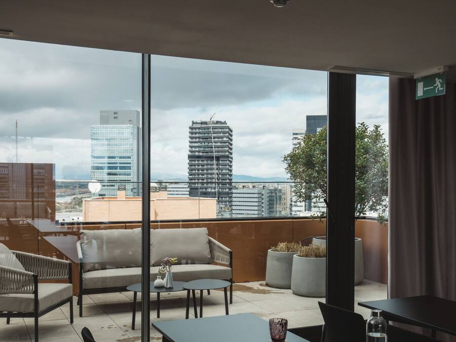 Un área de estar moderna en el interior con vistas al horizonte de la ciudad a través de grandes ventanales.