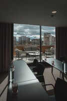 Habitación de hotel moderna con balcón, amoblada con sofá, sillas y una mesa de comedor.
