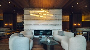 A modern lounge area with a central seating arrangement, a fireplace, and a unique hanging light fixture.