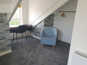 Cozy retreat with a sloped ceiling, featuring a desk, armchair, and window.