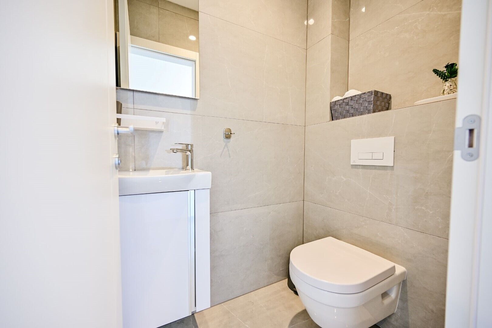 Un baño moderno con inodoro, lavabo y espejo.