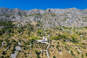A remote mountain property with terraced fields, a white building with a satellite dish, and rocky terrain. - Villa Mountain Lodge (Lokva Rogoznica)