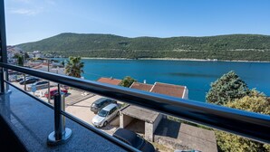 Ein Balkon mit Blick auf einen See, Gebäude und eine hügelige Landschaft.