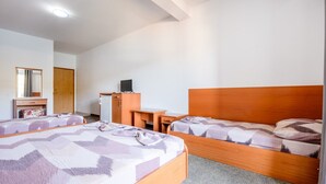 Ein Hotelzimmer mit zwei Betten, einem Schreibtisch, einem Spiegel, einem Kleiderschrank und einem kleinen Kühlschrank.