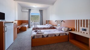 Ein Hotelzimmer mit zwei Betten, einem Schreibtisch, einem Fernseher und einem Balkon mit Blick.