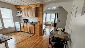 Una cocina amplia con armarios de madera, un comedor con mesa y sillas, y vista al salón.