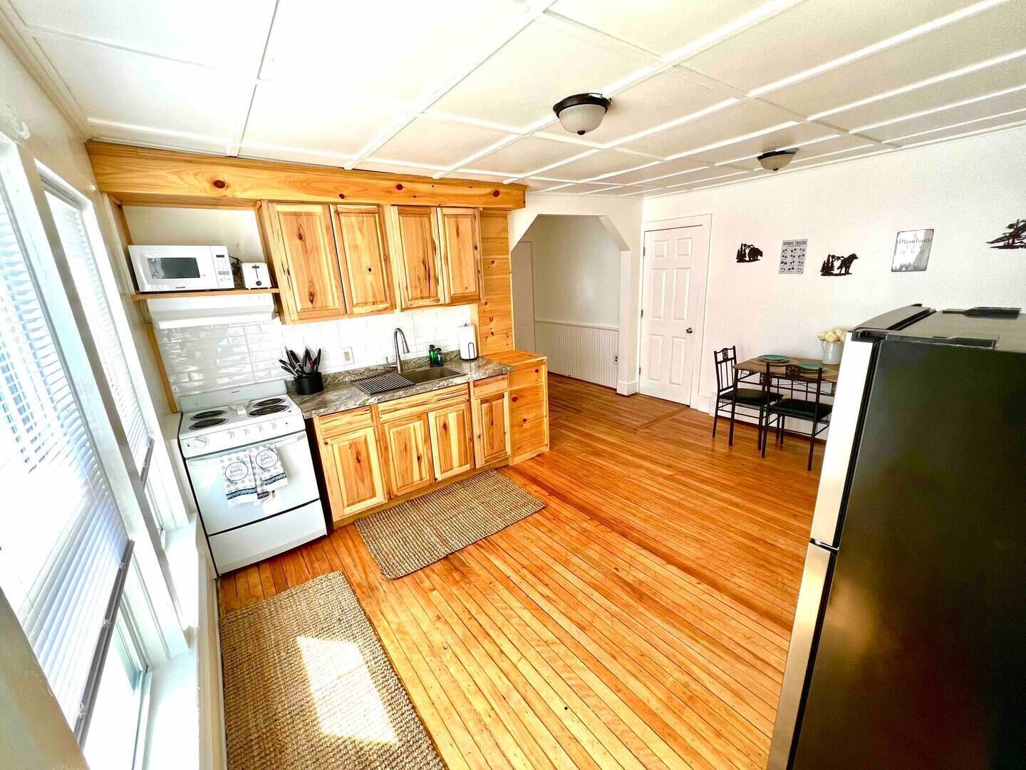 A compact kitchen with wooden cabinets, a stove, a microwave, and a refrigerator.