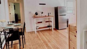 Una cocina amplia con piso de madera, un comedor con sillas y un refrigerador.