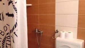 A bathroom with a shower curtain, a toilet, and a wall-mounted toilet paper holder. - Apartmani Kata / Studio apartment 3 on the ground floor (Neum)