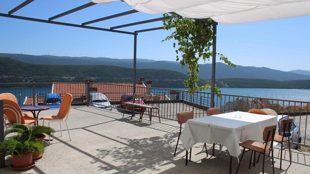 An outdoor terrace with tables and chairs, a white canopy, and a view of a lake and mountains. - Apartmani Kata / Studio apartment 3 on the ground floor (Neum)