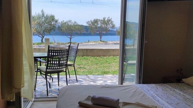 A bedroom with a bed, a chair, and a view of a lake and trees.