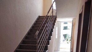 A staircase with metal railings leading to a bright hallway with tiled floors.