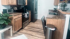 A modern kitchen with wooden cabinets, a microwave, a refrigerator, a stove, and a sink.