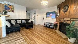 A living room with a black sectional sofa, a fireplace, and a television.
