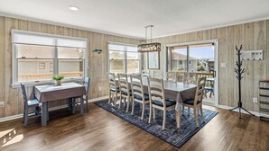 A dining area with a wooden table and chairs, large windows, and a ceiling fan. - Unforgettable! Saltwater Pool! Newly Renovated! Walk to Beach, D0131 (Duck)