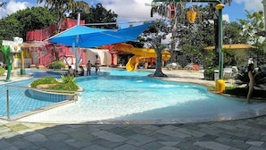 A swimming pool with a water slide, surrounded by a red and blue structure, and a covered seating area. - Diroma International Resort - Caldas Novas Goias (Chácara Roma Caldas Novas)