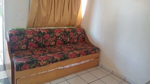 A sofa with a floral pattern, a beige curtain, and a framed picture on the wall. - Diroma International Resort - Caldas Novas Goias (Chácara Roma Caldas Novas)