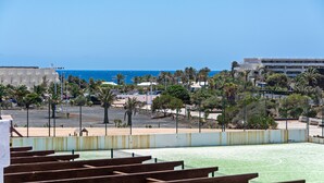 Cancha de tenis al aire libre con vistas al mar y palmeras.