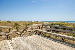A wooden boardwalk leading to a beach with a clear view of the ocean.