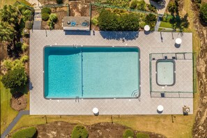 An aerial view of a rectangular swimming pool with a smaller pool adjacent to it, surrounded by landscaped areas and pathways.