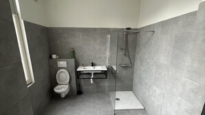 Une salle de bain moderne équipée de toilettes, d’un lavabo et d’une douche.