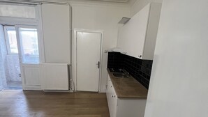 Une cuisine avec des meubles blancs, un dosseret en carreaux noirs et un plan de travail en bois.