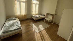 Une chambre avec deux lits simples, une petite table, un radiateur et une cheminée.