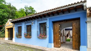 Un bâtiment à la façade bleue, doté de portes en bois et de fenêtres avec des barreaux en métal.