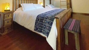 Une chambre à coucher avec un lit en bois, une table de chevet avec une lampe, un banc et une décoration murale.