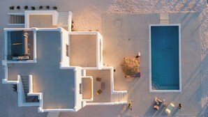 Vista aerea di un resort moderno con piscina, diverse camere e aree salotto all'aperto.