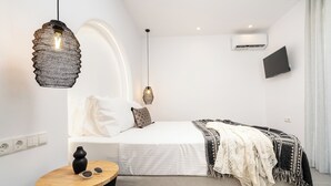 Una camera da letto moderna con un letto, un comodino e due lampade a sospensione.